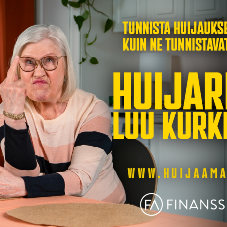 Nainen istuu pöydän ääressä keskisormi pystyssä.